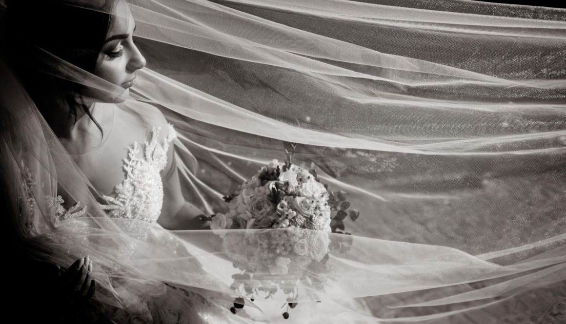 monochrome-view-tender-beautiful-bride-with-wedding-bouquet-long-veil-with-closed-eyes